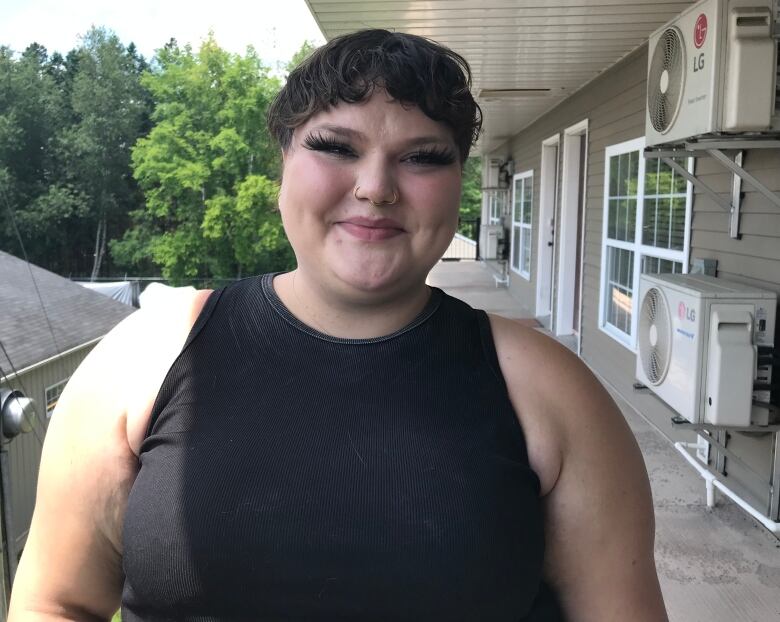 Woman with short hair in black tank top smiles at the camera.