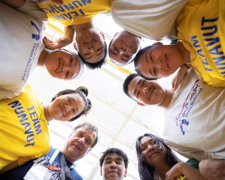 Athletes in a circle pose in front of the camera. 