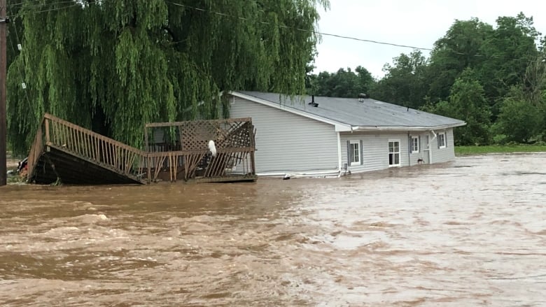 A house and separated deck are seen in the floodwaters of Windsor, N.S.