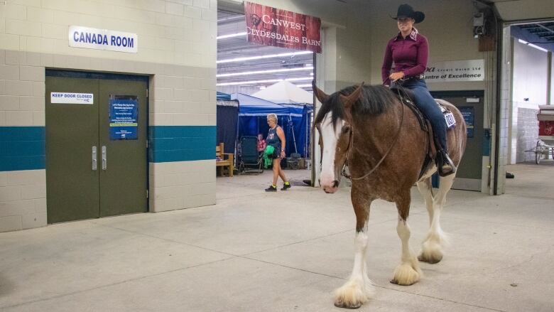 A woman rides a giant horse.