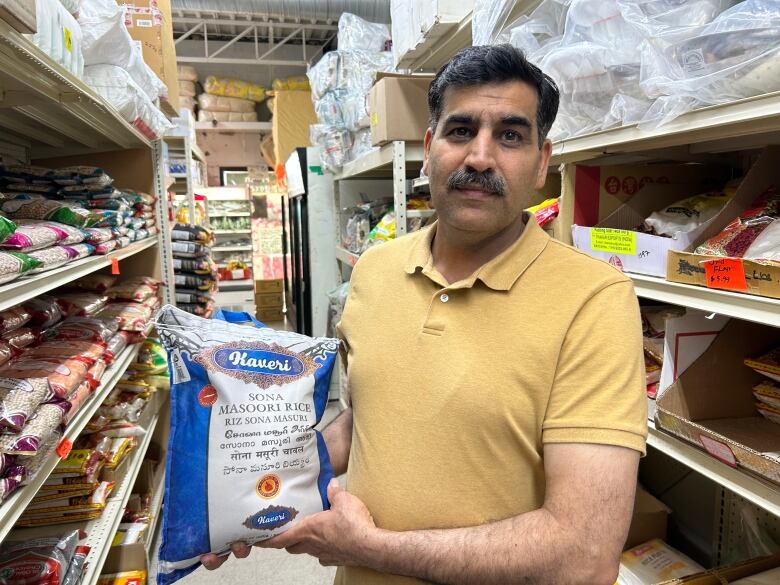 A man in a yellow shirt hold a rice bag.