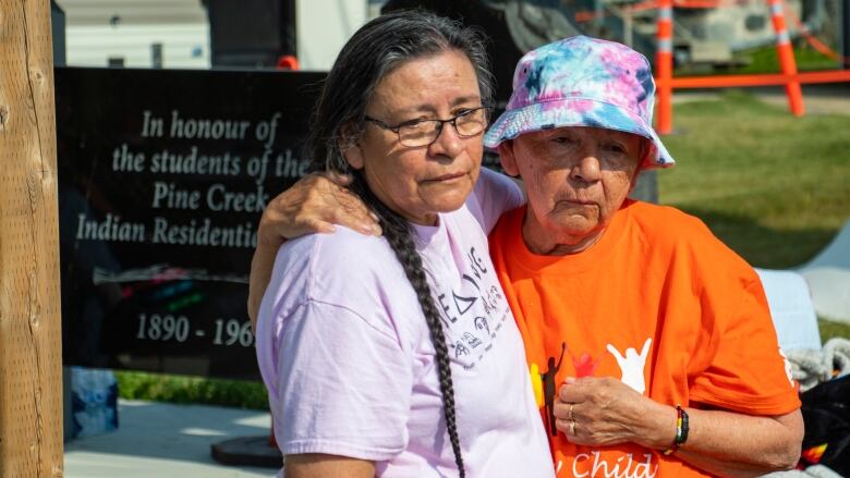 Two women embrace.