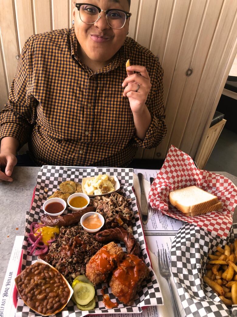 A woman smiles at a plate of barbecue