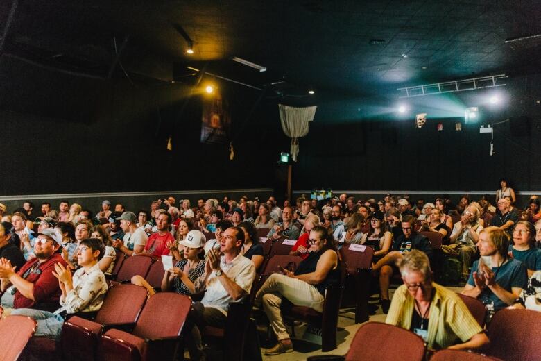 People pack a theatre to watch a movie.