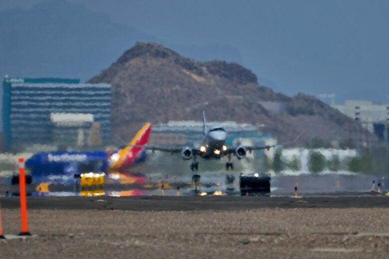 A plane with two jet engines takes off from a runway that has the illusion of being wet from heat distortion.