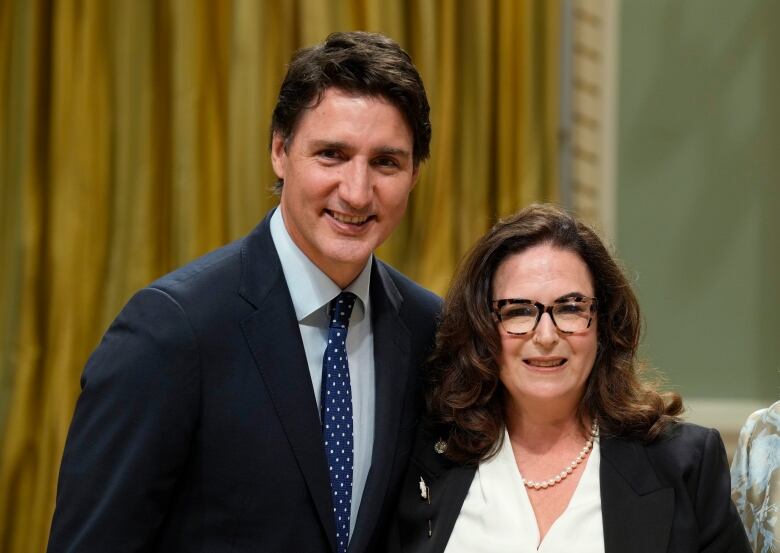 Prime Minister Justin Trudeau poses for a photo with Minister of Mental Health and Addictions and Associate Minister of Health Yaara Saks. He is wearing a dark suit and bue tie. She is wearing a dark blazer and white blouse.