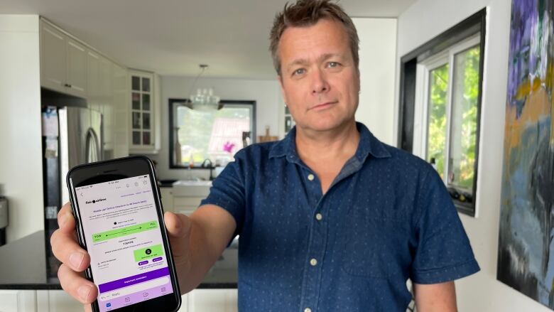 Jamie Christensen holds up an email from Flair Airlines prompting him to check-in to his May 13 flight to Fort Lauderdale, F.L. When he arrived at the Ottawa Airport the next day, he was told there was no such flight.