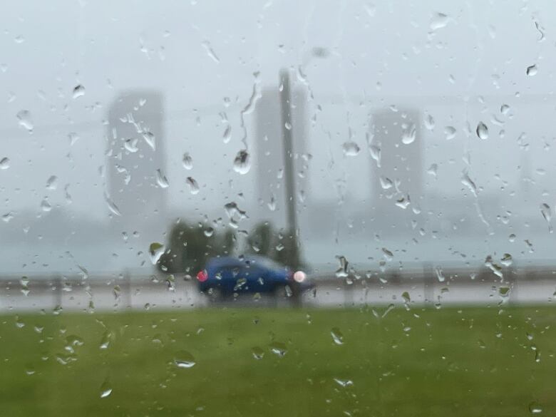 Rain on a window as a car rushes down the street on the other side