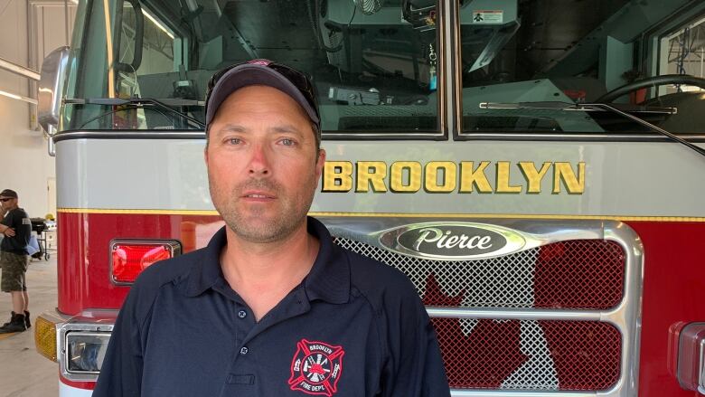 A man stands in front of a fire truck.