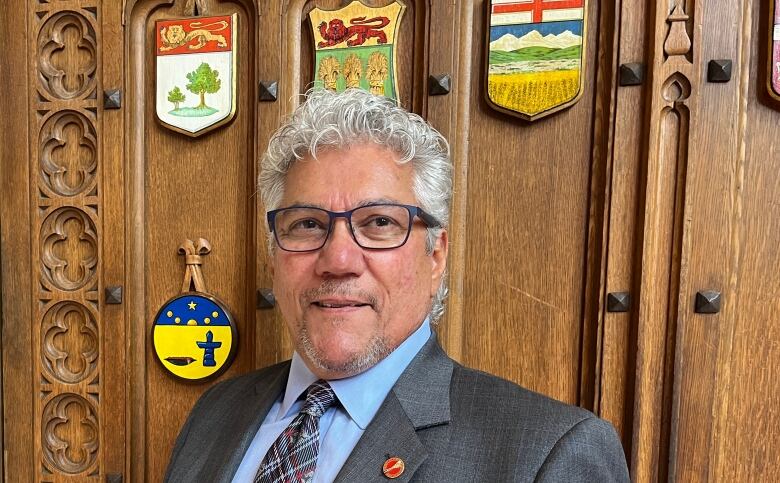 A man in a suit underneath the Saskatchewan crest.