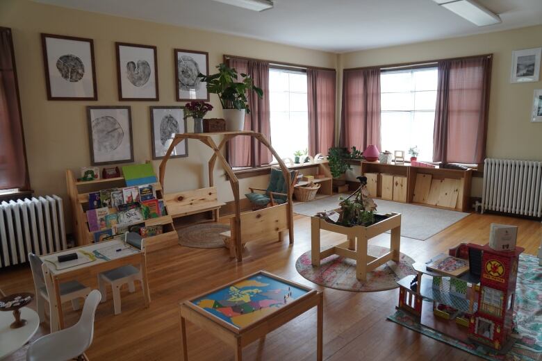 The inside of Nature's Nest Preschool, which has soft-yellow walls, wooden toy and tables, books, chairs and carpet.