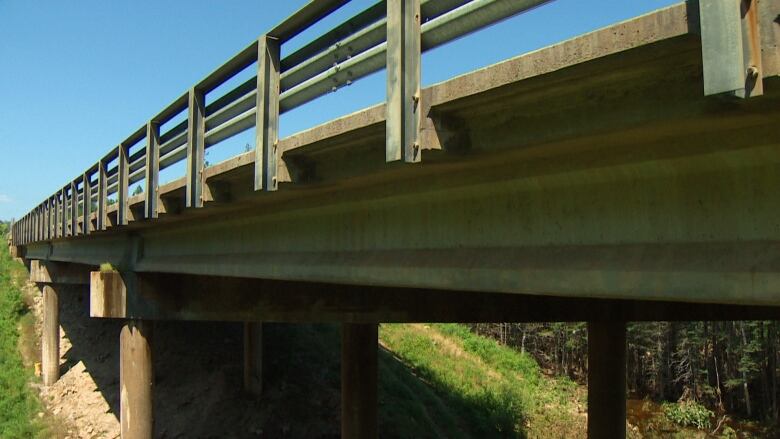 A metal and concrete bridge over a small river is shown.