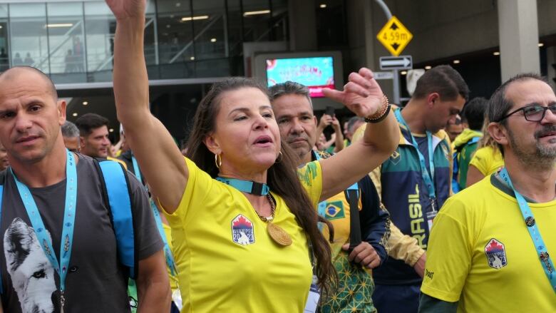 A women sings and dances as she walks down a street in a crowd of people.