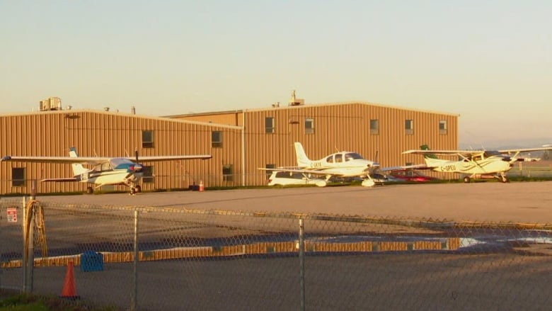 Airplanes parked in front of a brown building. 