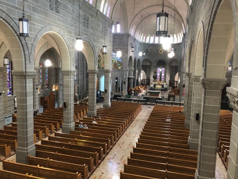 The interior of a cathedral with wooden pews and grey brick archways