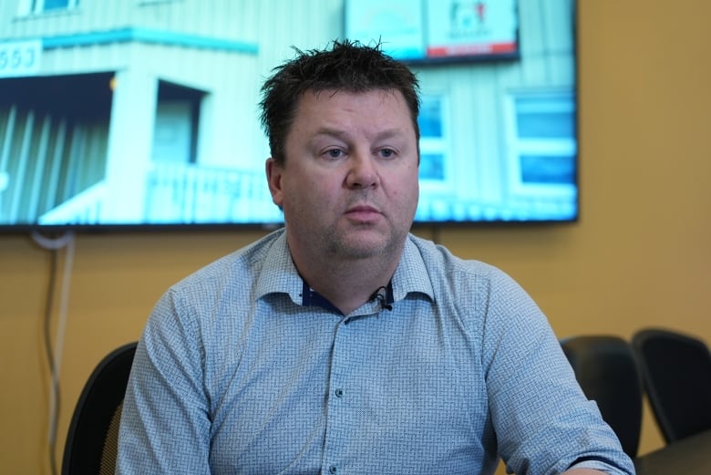  Iqaluit Housing Authority Board of Directors Chair Eiryn Devereaux sits in front of a screen wearing a grey shirt.