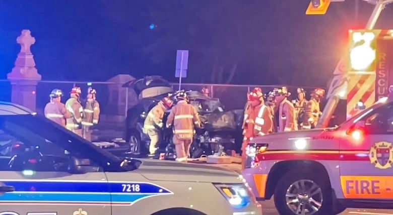 Police and emergency crews surround a vehicle that is badly damaged. 