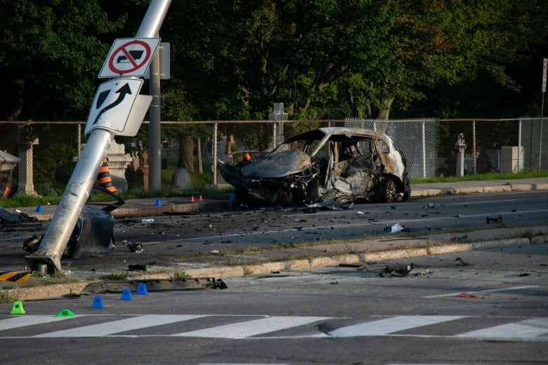 A charred car and a traffic pole leaning to the side.