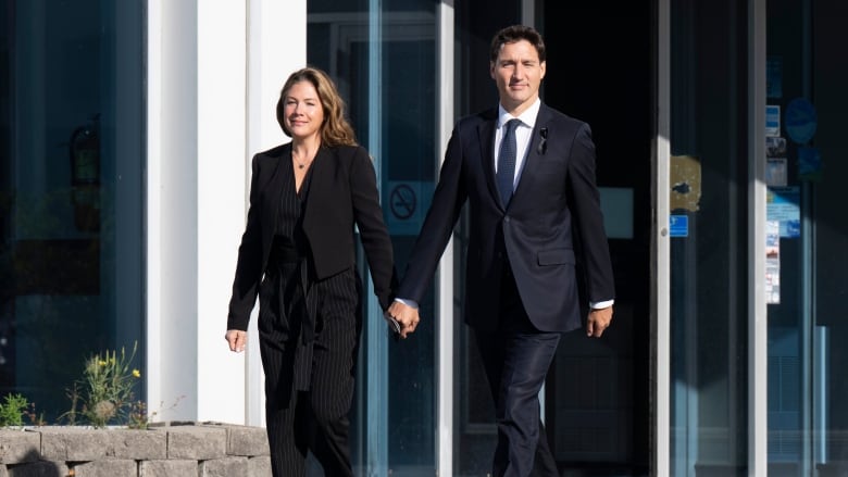 A man and a woman walk holding hands.