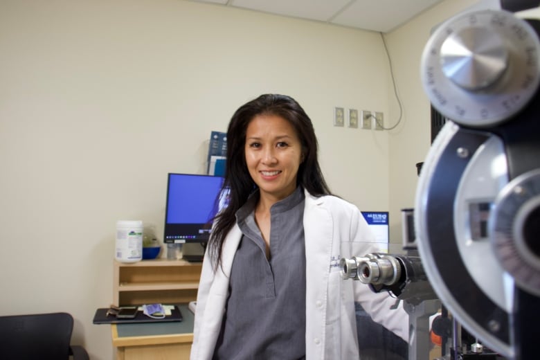 A woman stands by an eye examination station.