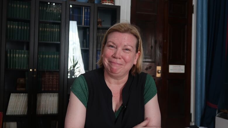 A woman in a green top smiles at the camera.