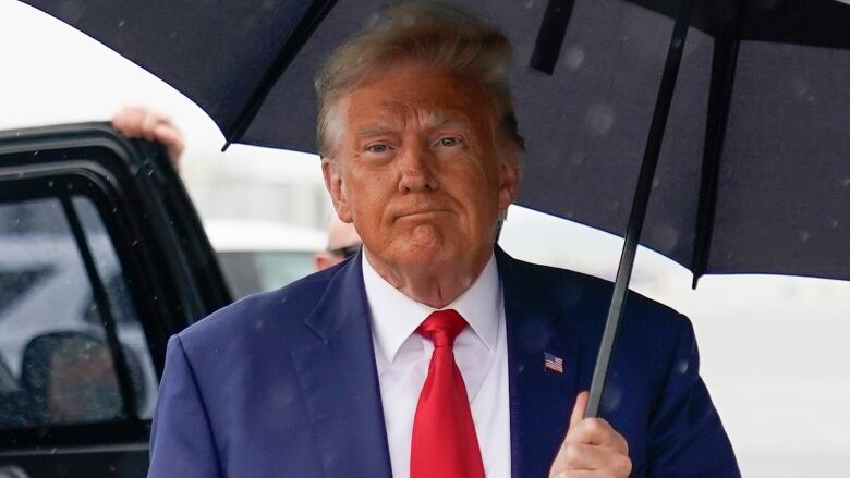 A man who is holding an umbrella looks sad.