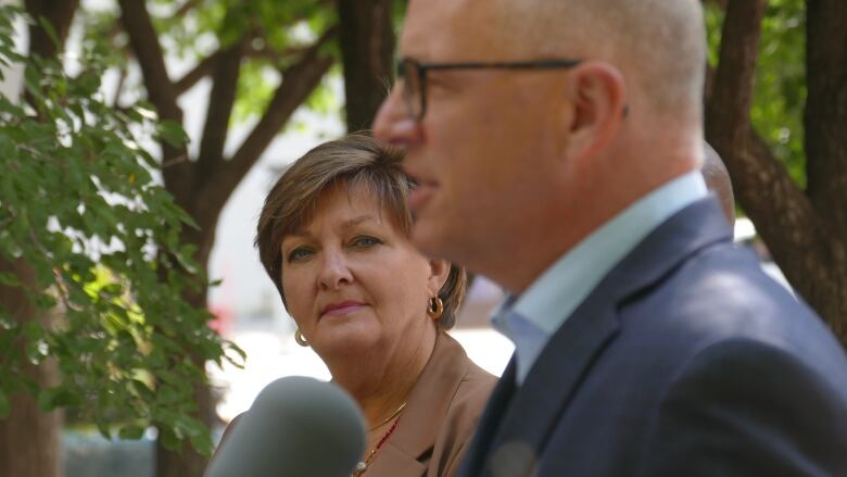 A woman is looking at a man who is speaking into a microphone.