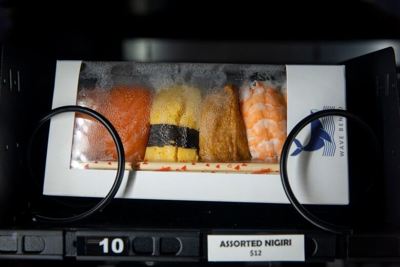 A box of nigiri on sale in a vending machine at a Coquitlam SkyTrain station. A label reads: Assorted nigiri, $12.