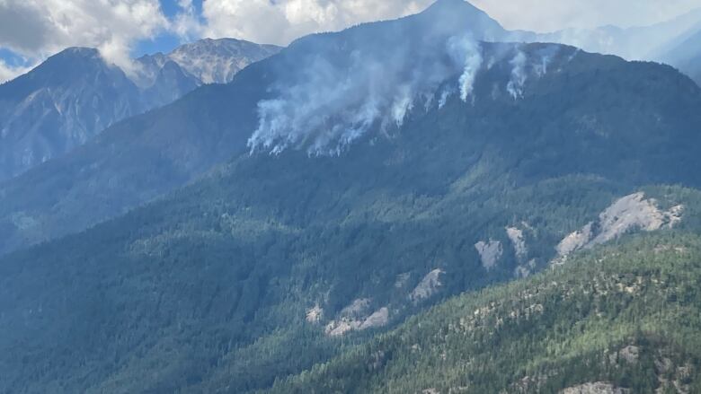 Smoke plumes are seen at the top of a mountain.