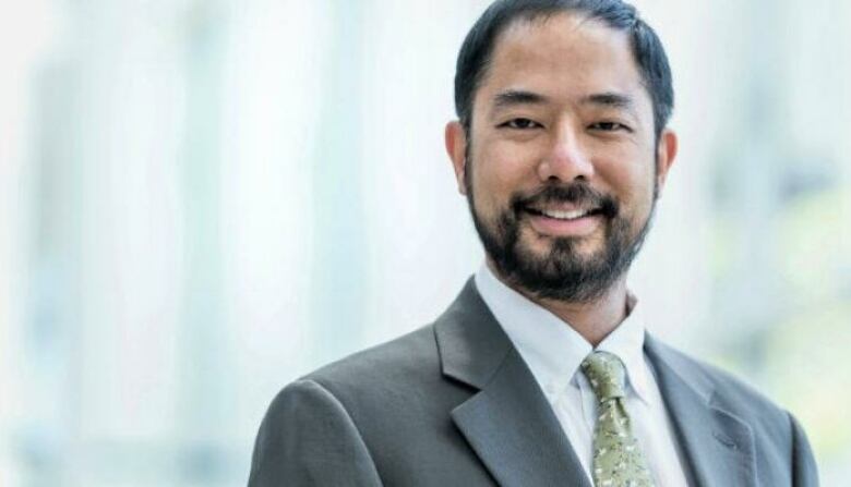 A man in a suit smiles in a headshot.