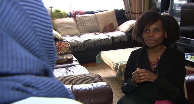 a woman speaks to a reporter in her living room