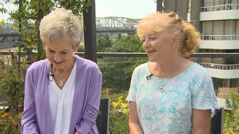 Two white women  one with short white hair, and the other with curly brown hair  share a laugh.