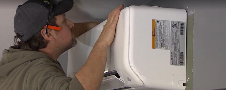 Closeup of man pushing on indoor head of heat pump 