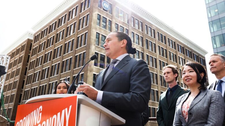 A man at a suit in a podium on a rooftop.