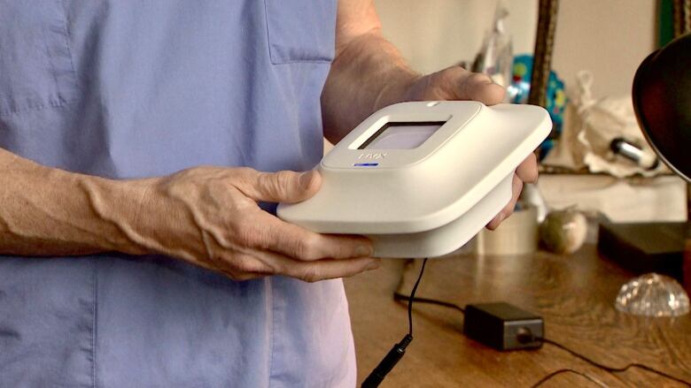 Hands hold a device that looks like a white smoke detector. It is actually a UV lamp that shines light up to 500 square feet. 