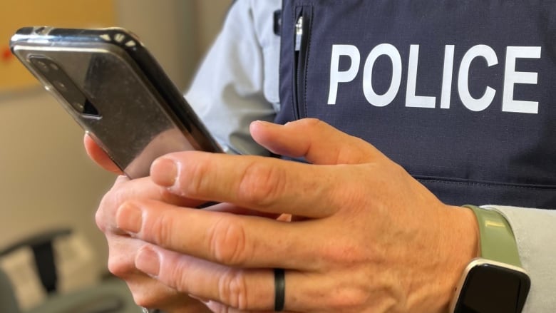 A police officer holds a cellphone.