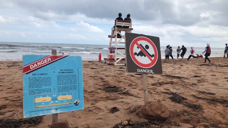 PEI Lifeguard on a beach with rip current and danger sign.