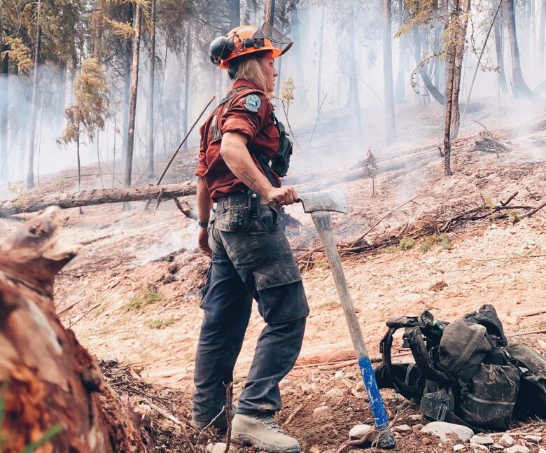 A woman stands in the middle of a forest. 