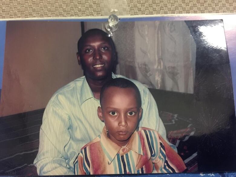 A man sits with a young boy on his lap as they pose for a photo