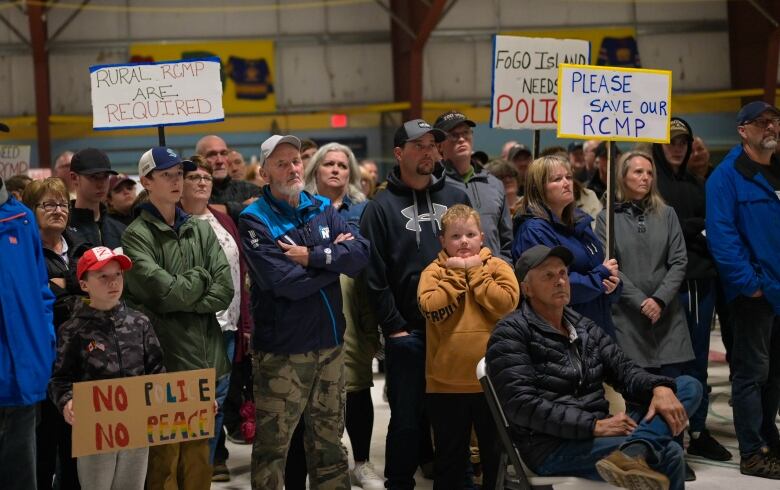 A large crowd full of young and old stares off to the left.