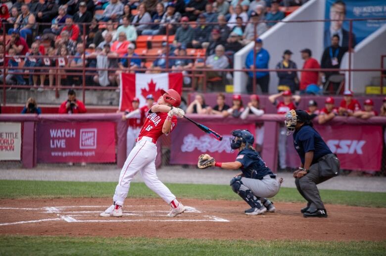 A woman swings a bat at home plate.