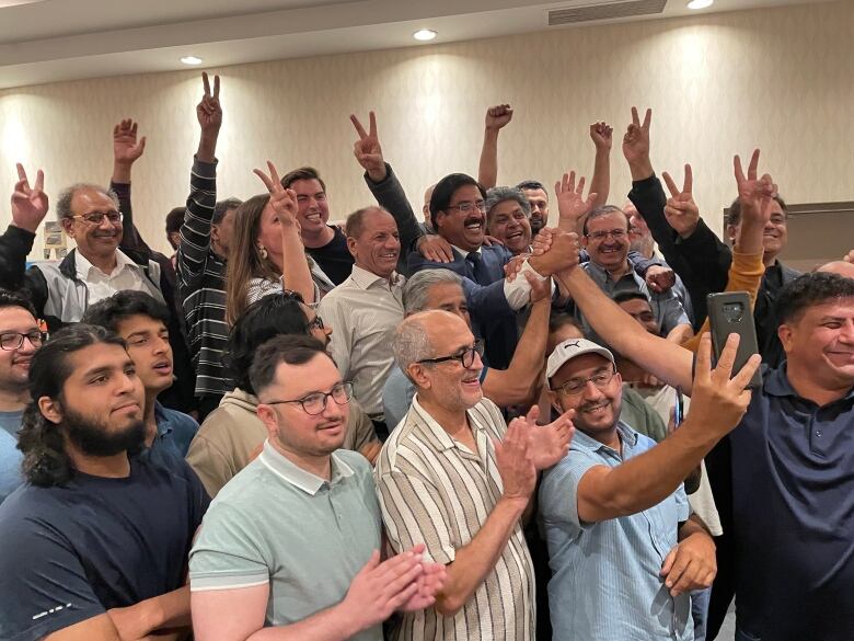 A man posing for a selfie in a group.