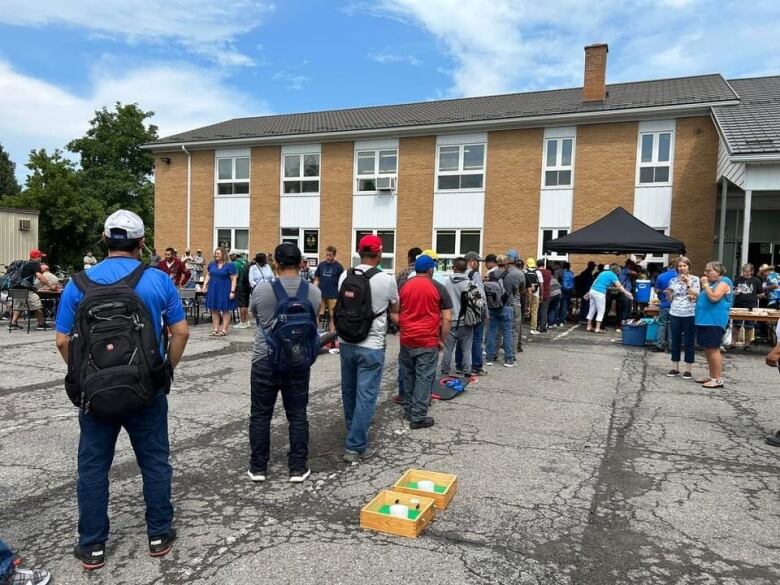 Men standing in line at a parking lot.