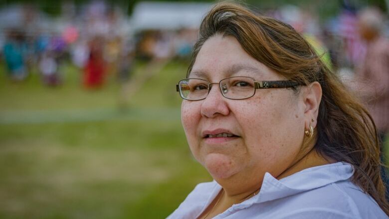 An Indigenous women with glasses peers into the camera. 