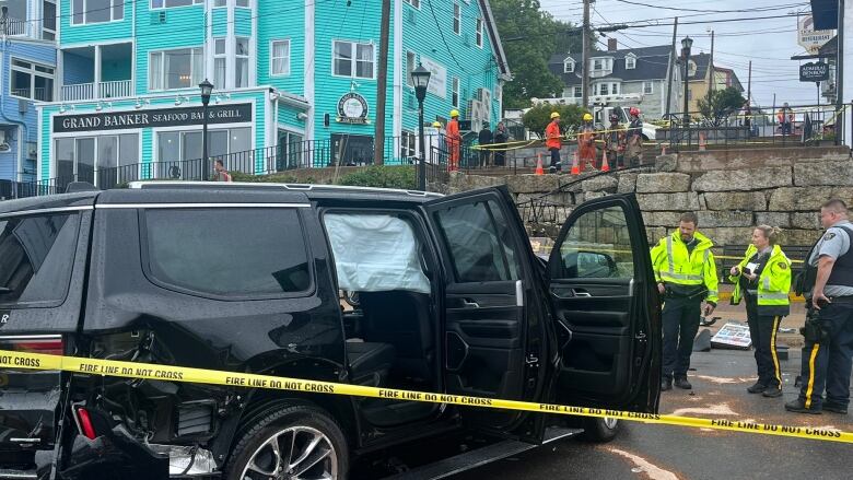 A black vehicle with all airbags deployed sits at the scene of an accident. The wall the vehicle flew off can be seen in the background.