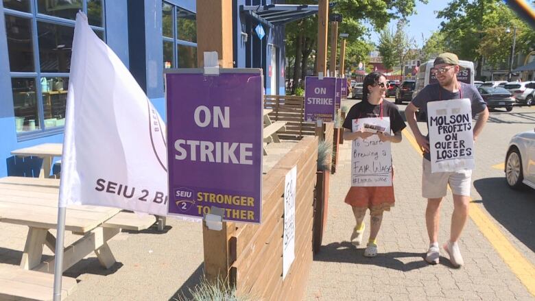 Two workers at Granville Island Brewing walk a picket line in downtown Vancouver with signs that say 