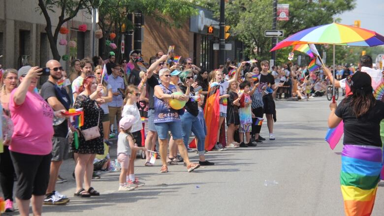 People standing on a street in support of a pride parade