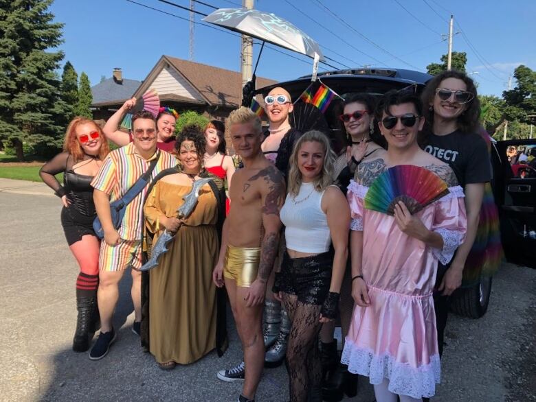 A group of people showing off pride-friendly items standing in front of a van