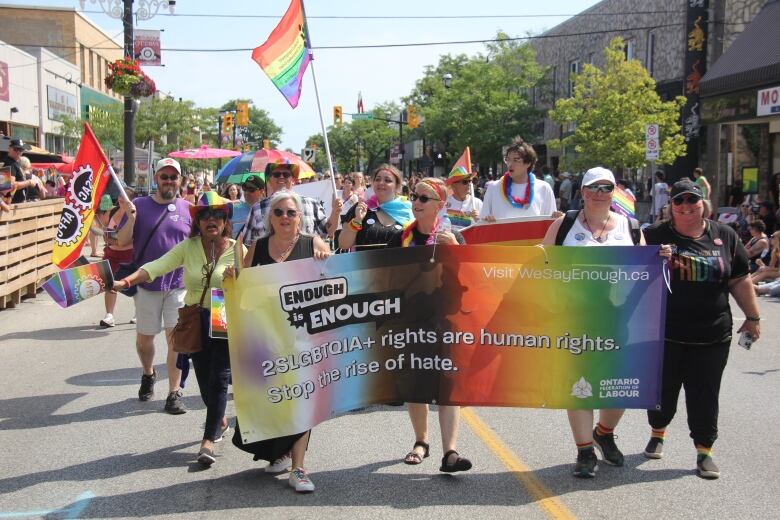 Pride parade marchers carrying banners with branding of their unions