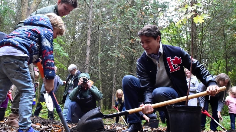 A family plants a tree in the woods.